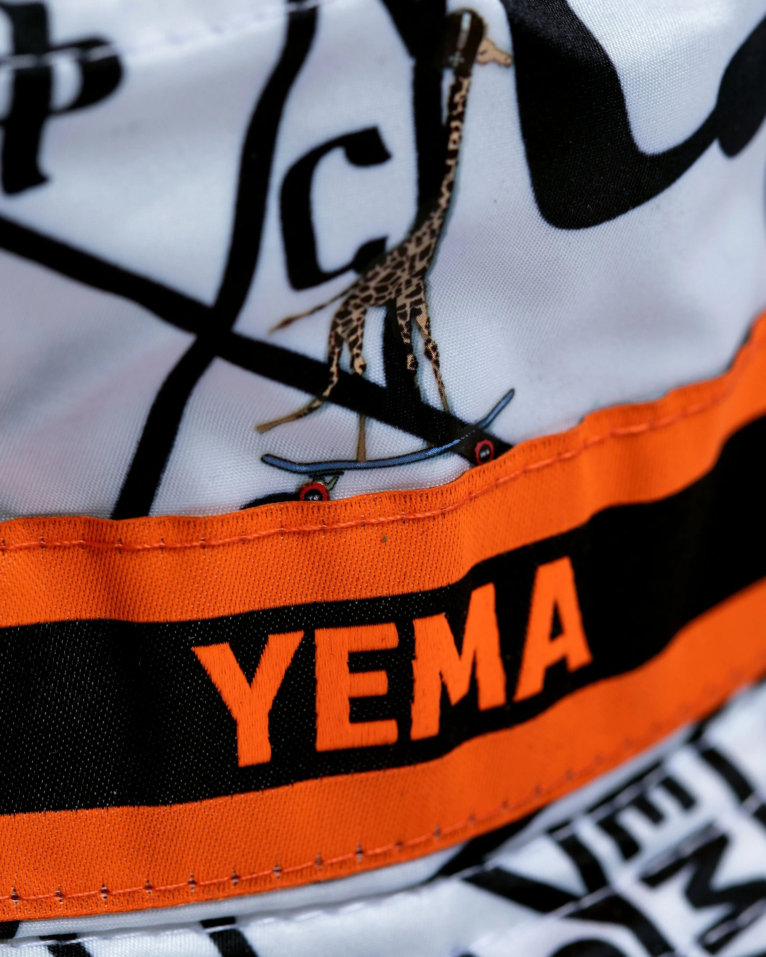 Detail of orange and black signature stripes on YEMA heritage bucket hat