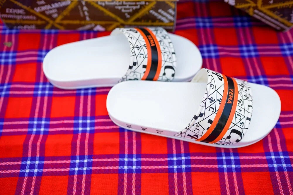 YEMA FIKIR slides in white featuring Amharic love pattern and signature orange black stripes