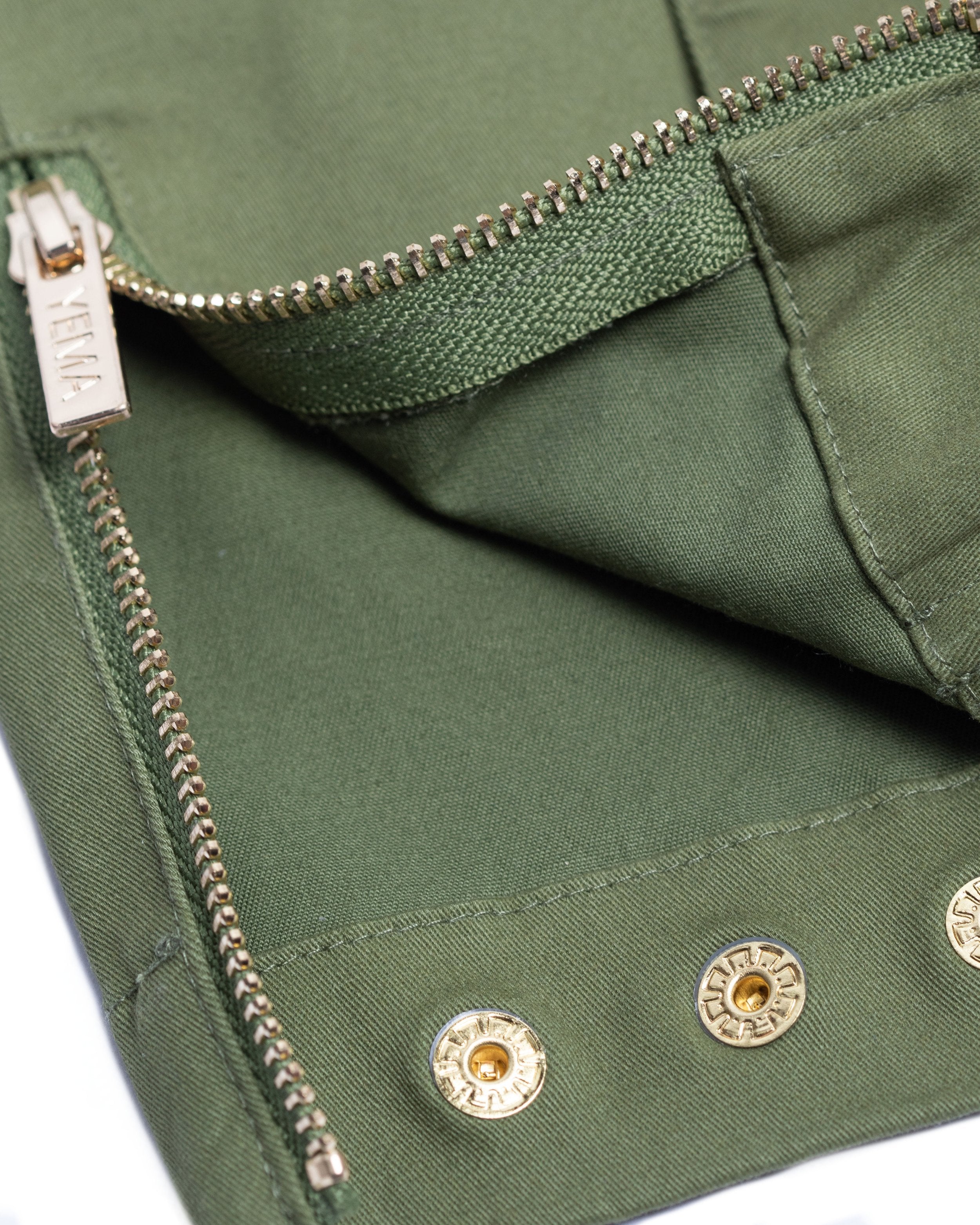 Detail shot of gold buttons and luxury hardware on YEMA GJH jumpsuit in olive
