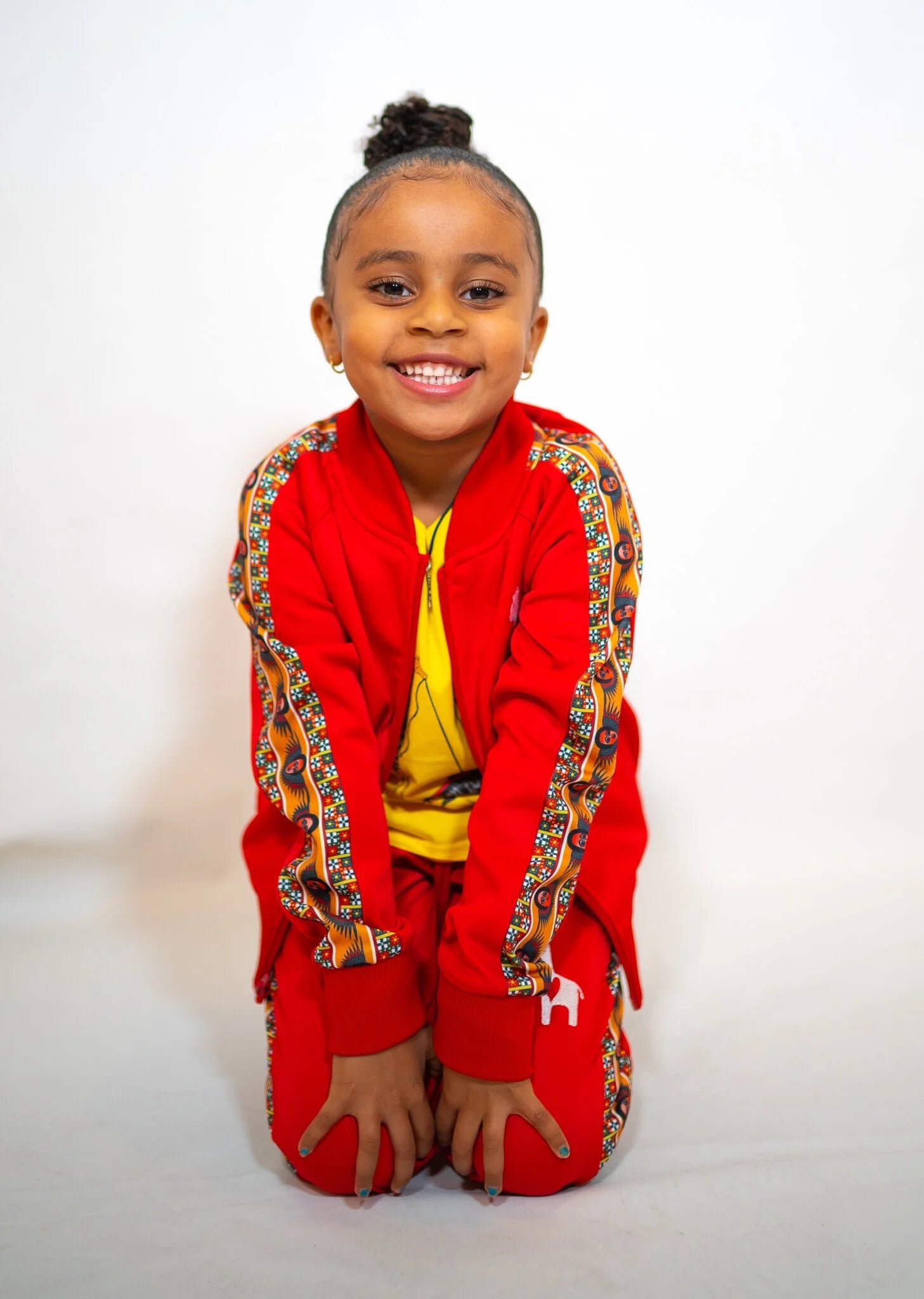 Child wearing Lali Red track jacket showing Abyssinian angel design and tricot polyester construction