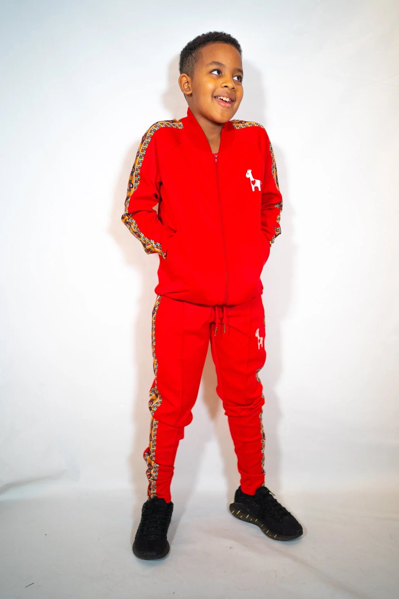 YEMA Kids Classic Track Pants in Lali Red featuring 17th-century Abyssinian angel motif and giraffe logo