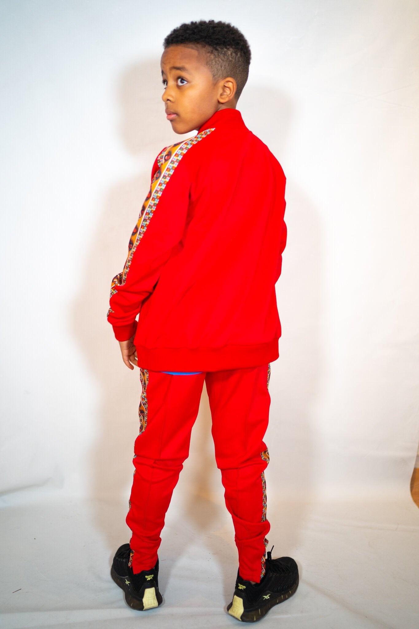 Kids' track pants with YEMA giraffe logo and Lali Red colorway honoring Lalibela, Ethiopia